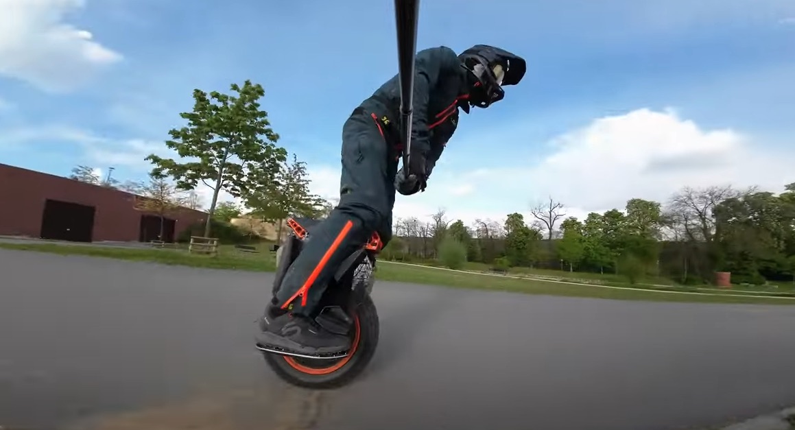 Image of a man riding Electric unicycle Begode Extreme 50s on the street and filming himself from selfie stick.