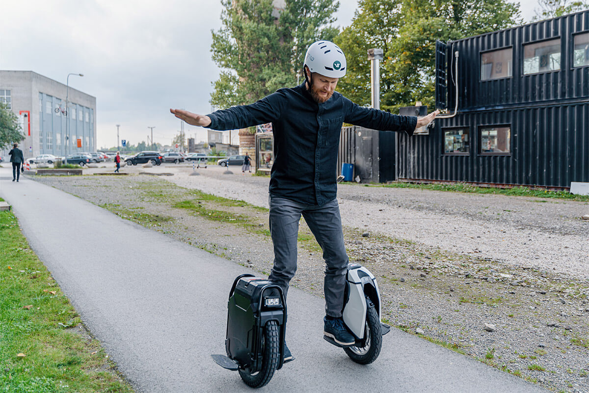 Voltride founder Mart Einpalu riding two electric unicycles simultaneously on a city street, demonstrating balance and control.