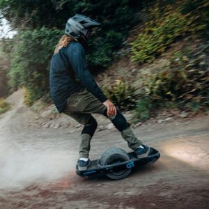 Man riding the Onewheel GT S Rally Edition in the forest wearing a full face helmet.