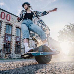 Girl riding the Onewheel XR Classic on offroad wearing a helmet.